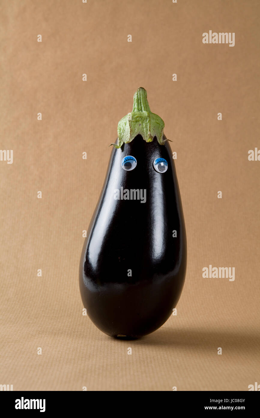 still life photography. Eggplant with eyes doll isolated on a kraft ...