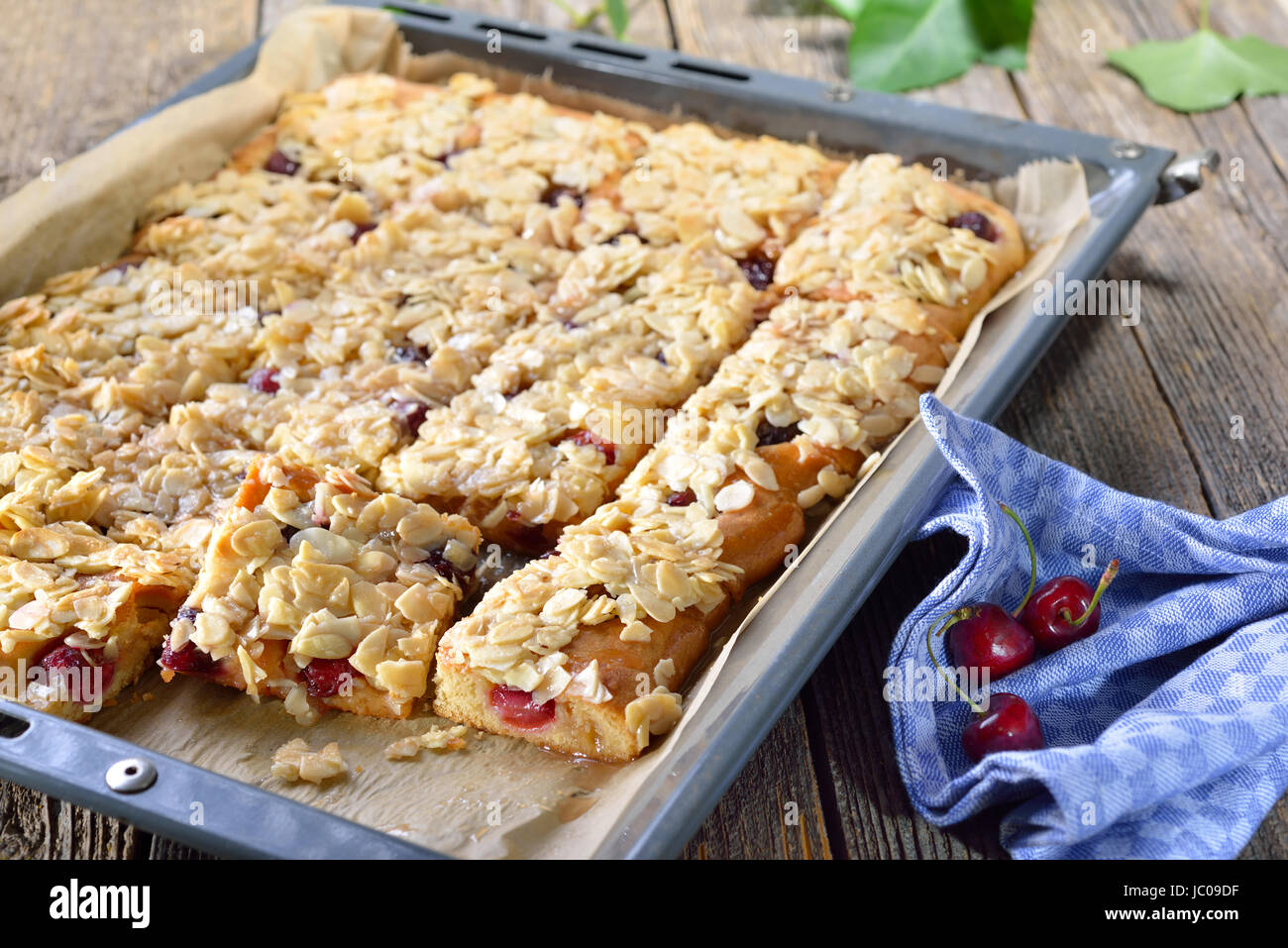 Yeast cake with fresh cherries  and crunchy almond caramel on a baking sheet Stock Photo