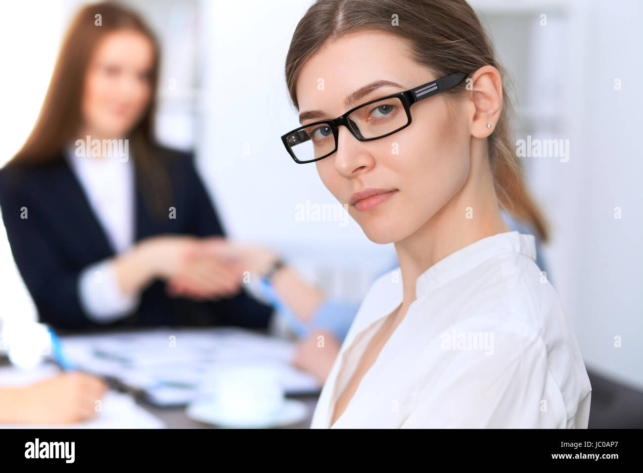 Portrait of a young business woman against a group of business people ...
