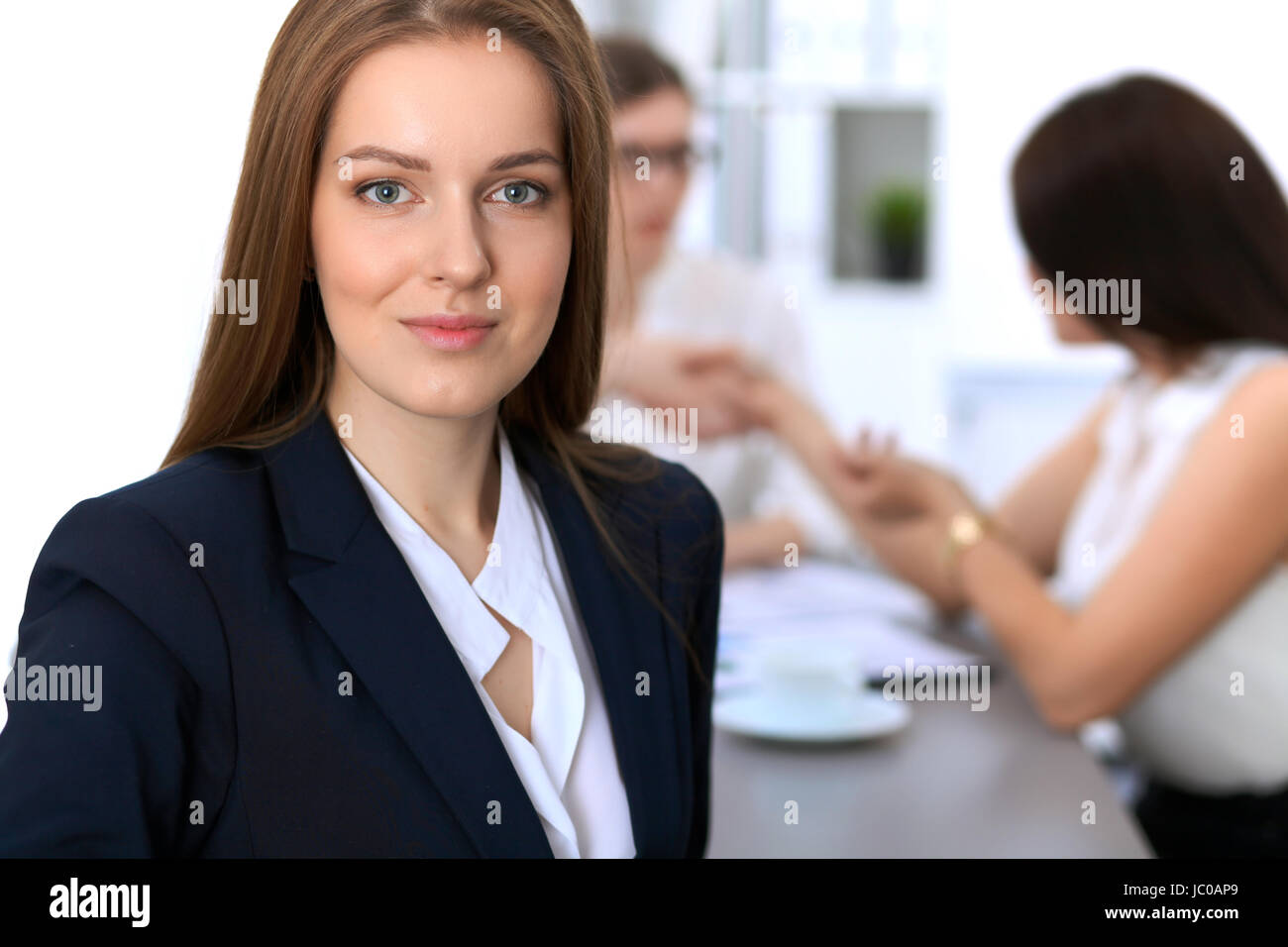 Portrait of a young business woman against a group of business people ...