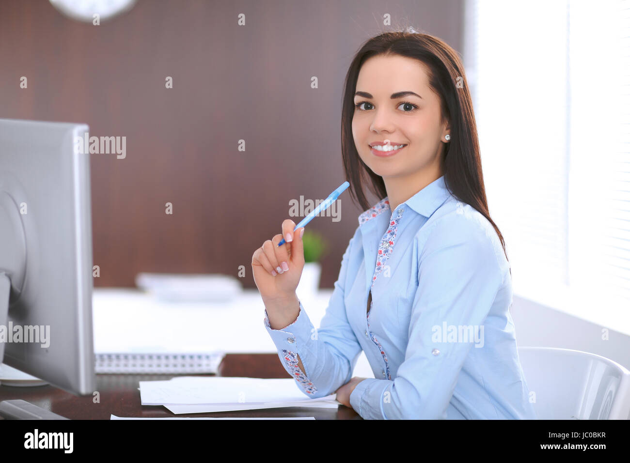 Young business woman sitting a at the table in office Stock Photo - Alamy