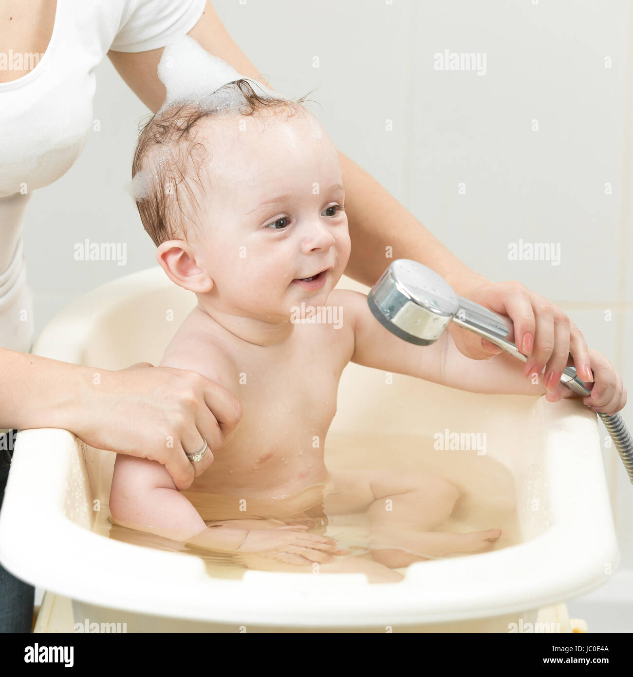 Closeup photo of mother bathing her cute baby in bathroom Stock Photo