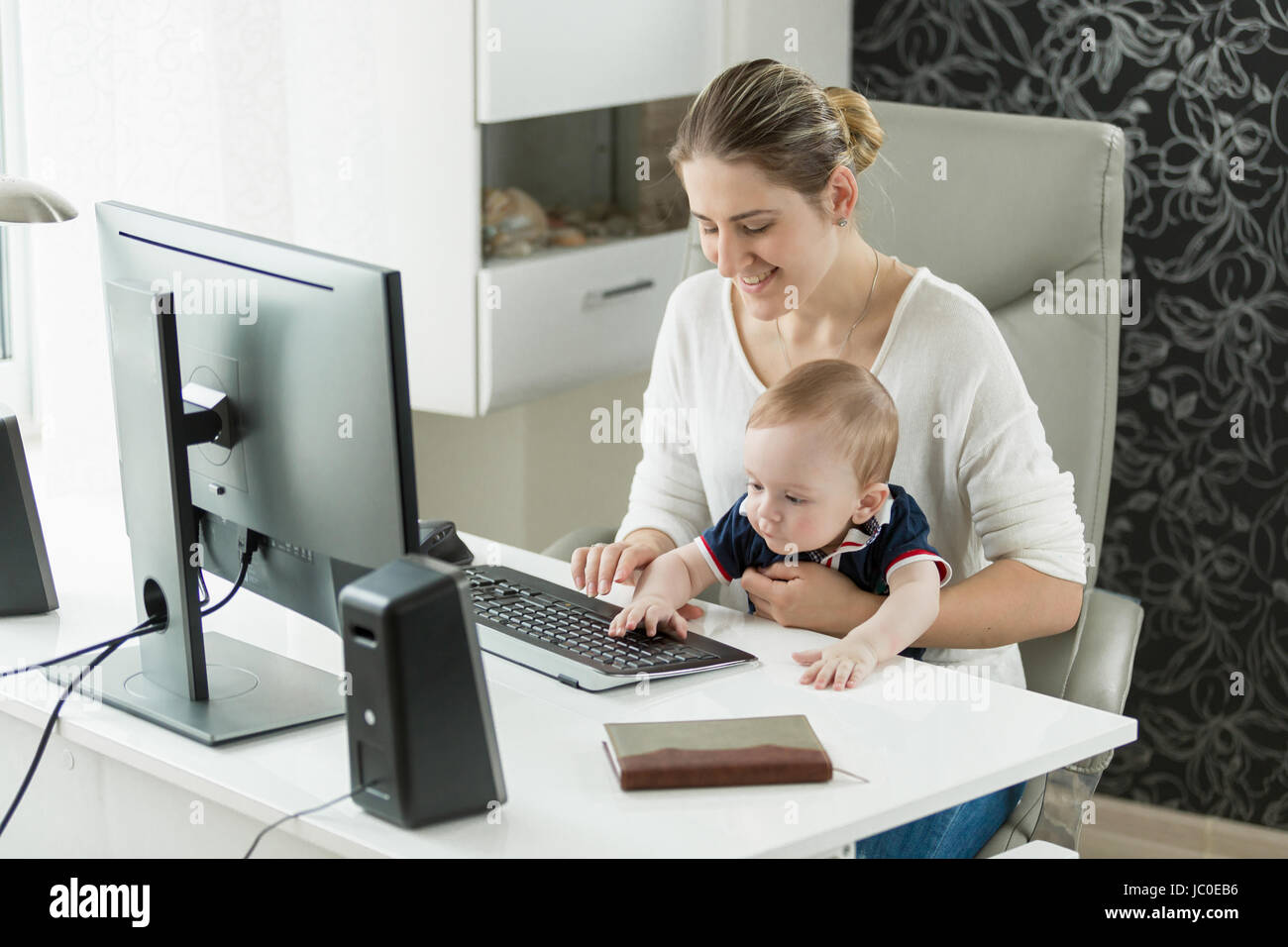 Portrait of smiling businesswoman working at computer with baby boy ...