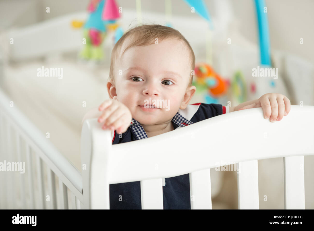 Portrait of 9 month old boy teething and posing in white cradle Stock