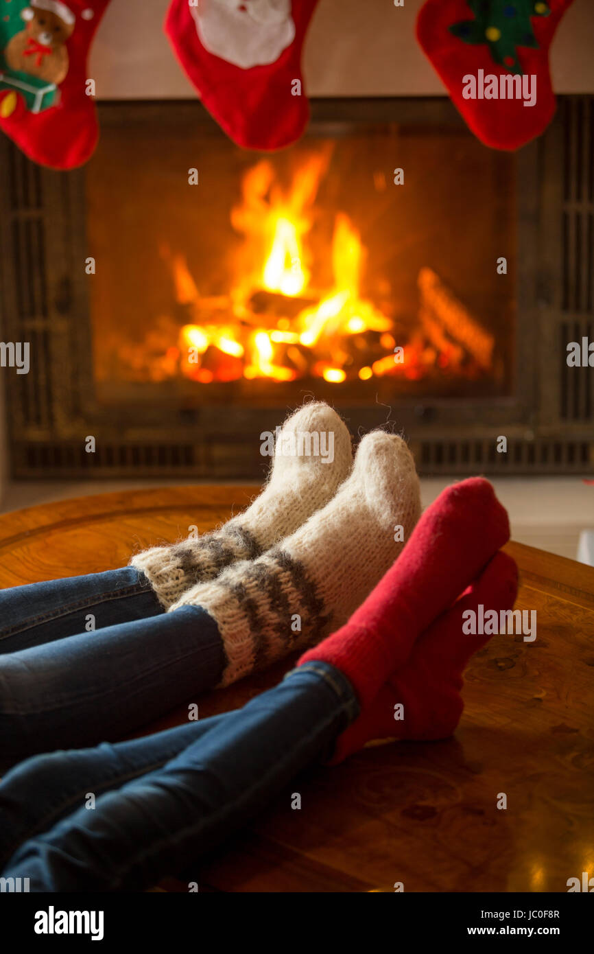 Closeup image of male and female feet in woolen socks warming at