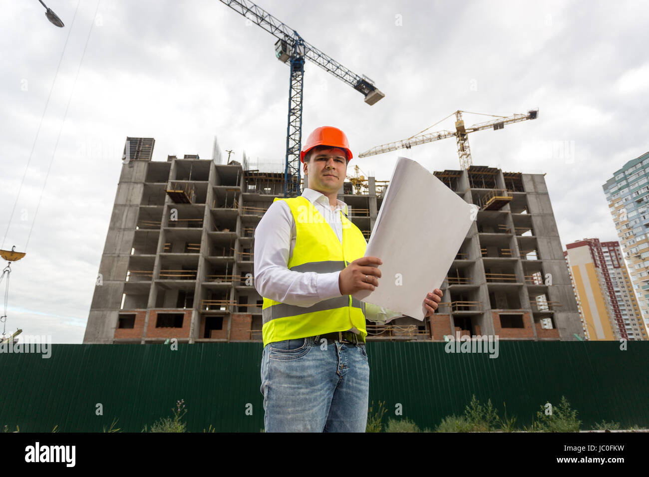 Portrait of engineer on building site with blueprints Stock Photo - Alamy