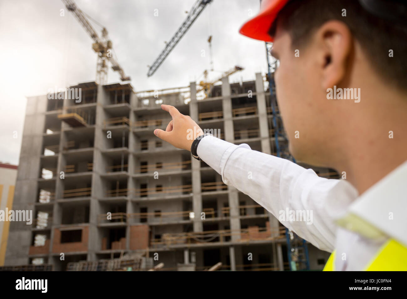 Closeup image of construction engineer pointing with hand at building ...
