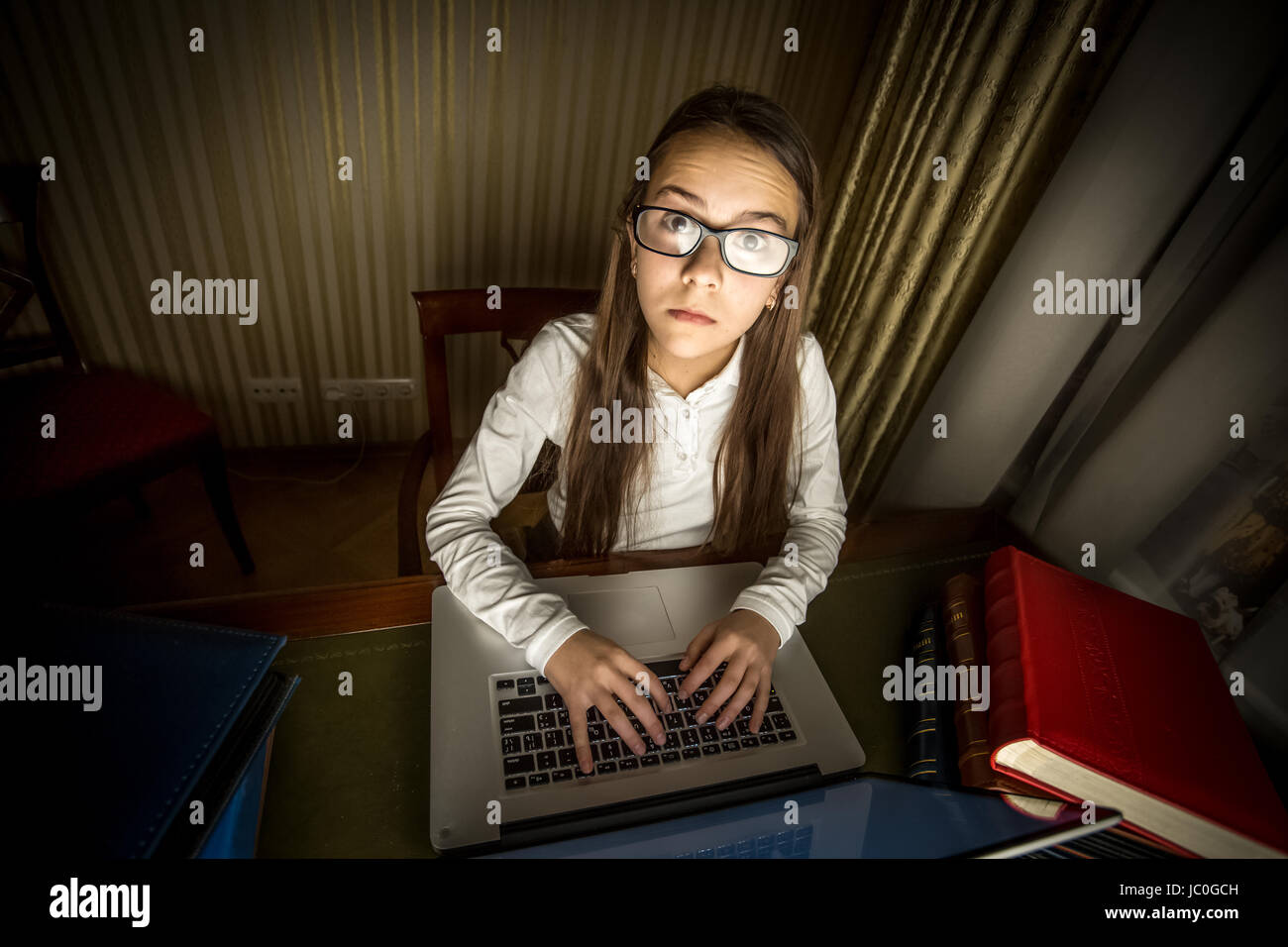 Funny portrait of computer geek girl sitting at laptop at night Stock Photo