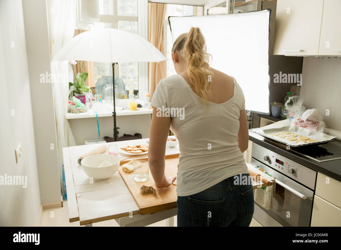 Rear view of woman preparing food for culinary blog. Photography equipment standing on kitchen Stock Photo