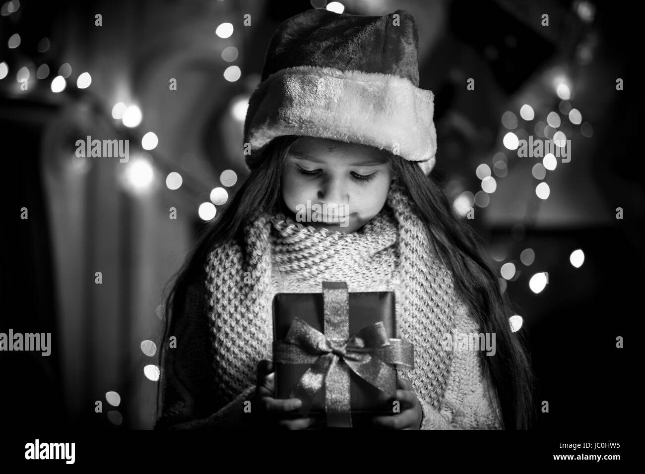 Black and white portrait of smiling girl opening Christmas present box Stock Photo