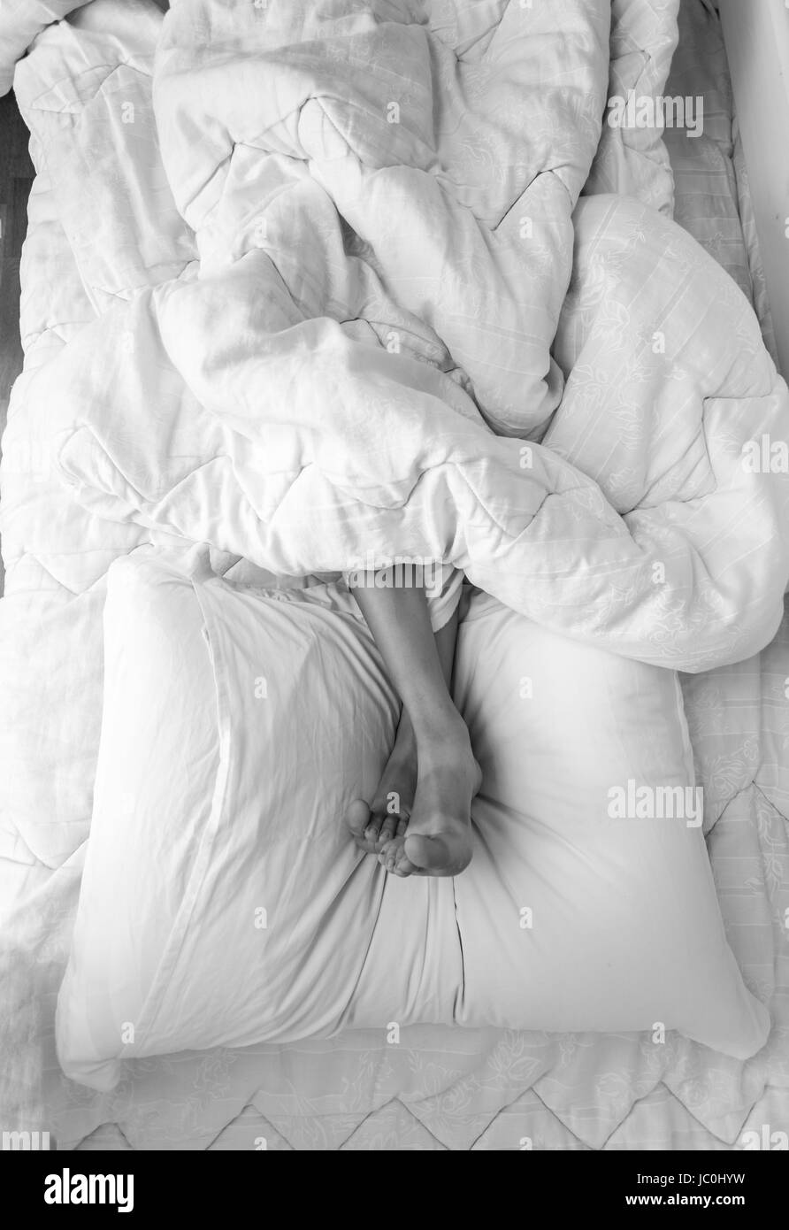 Black And White Shot Of Girls Feet Lying On Pillow At Bed Stock