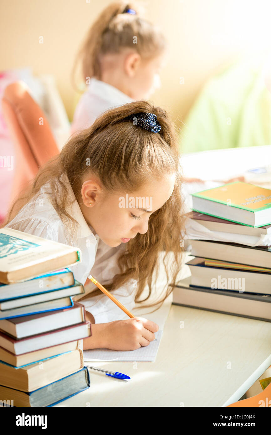Portrait of brunette girl sitting in class and writing in exercise book Stock Photo
