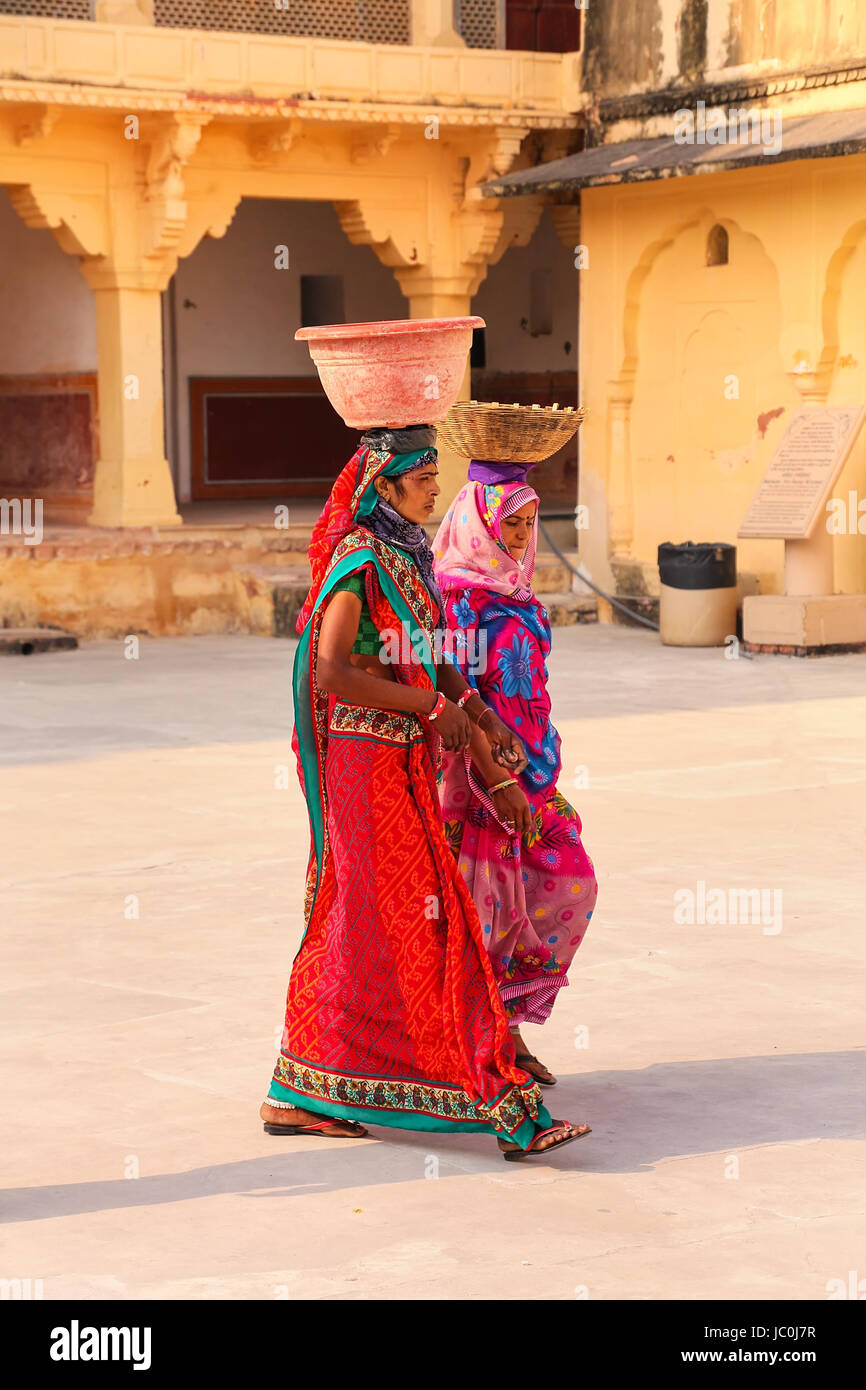 Local women walking with pots on their heads in the second courtyard of Amber Fort, Rajasthan, India. Amber Fort is the main tourist attraction in the Stock Photo
