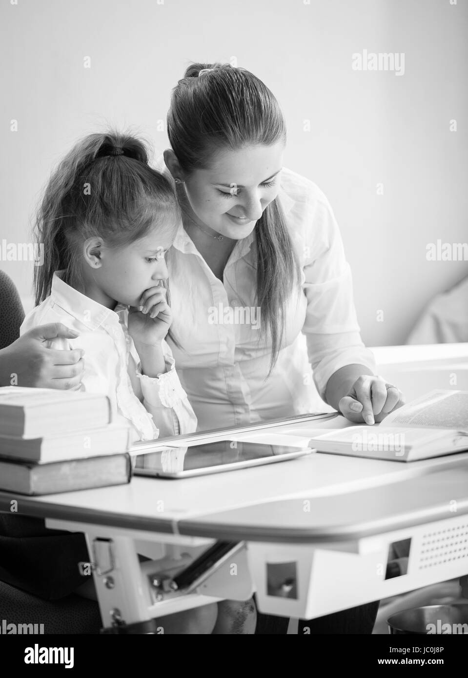 Monochrome portrait of happy mother and daughter doing homework Stock Photo