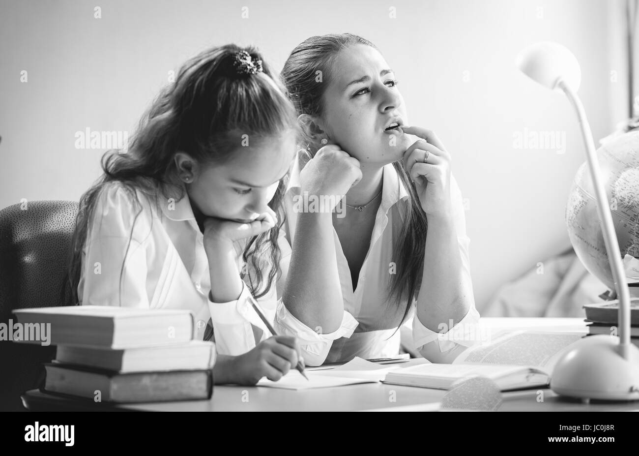 Black and white portrait of mother and daughter trying to solve exercise Stock Photo