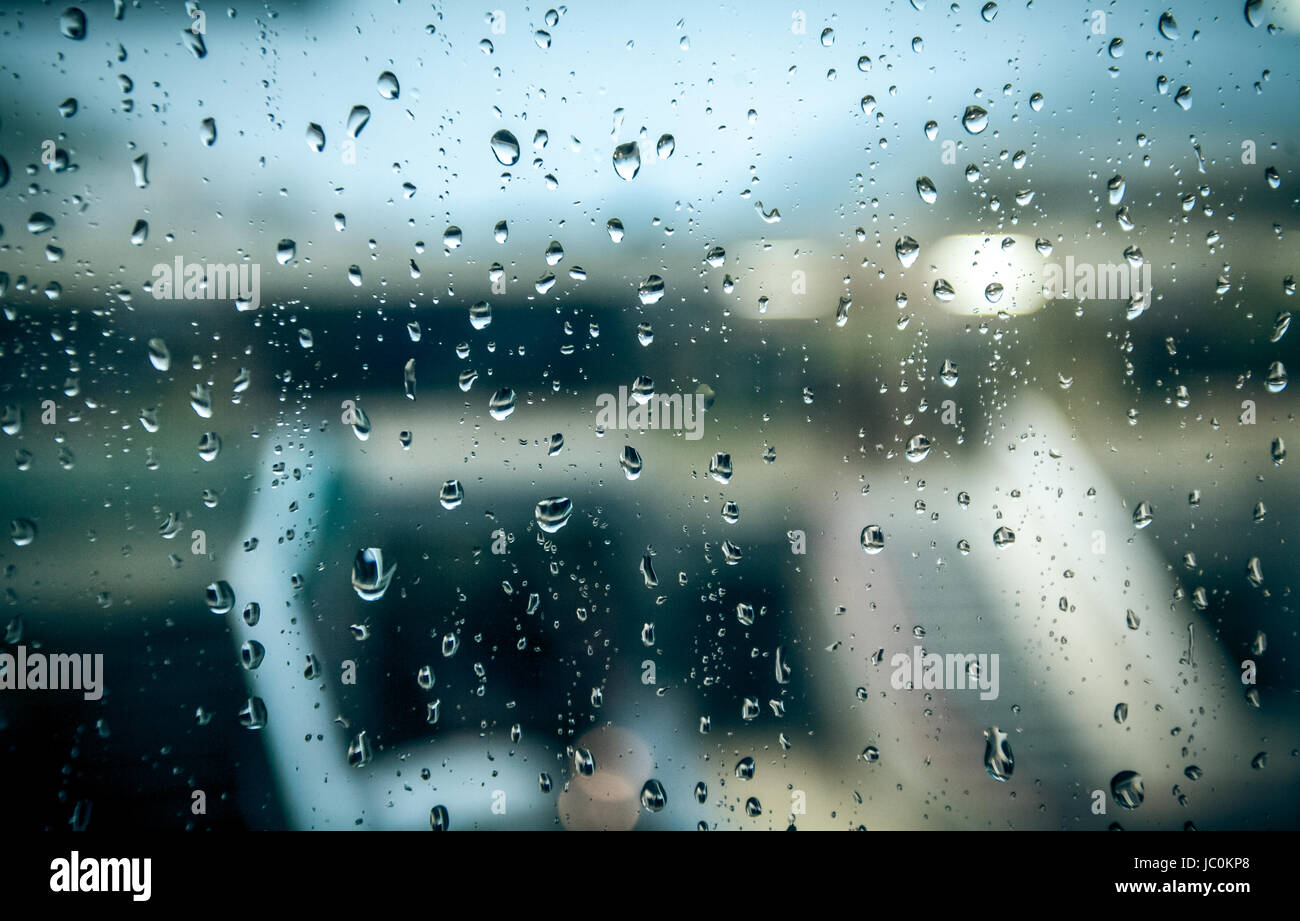 View on wet street at rainy day through window with water drops Stock ...