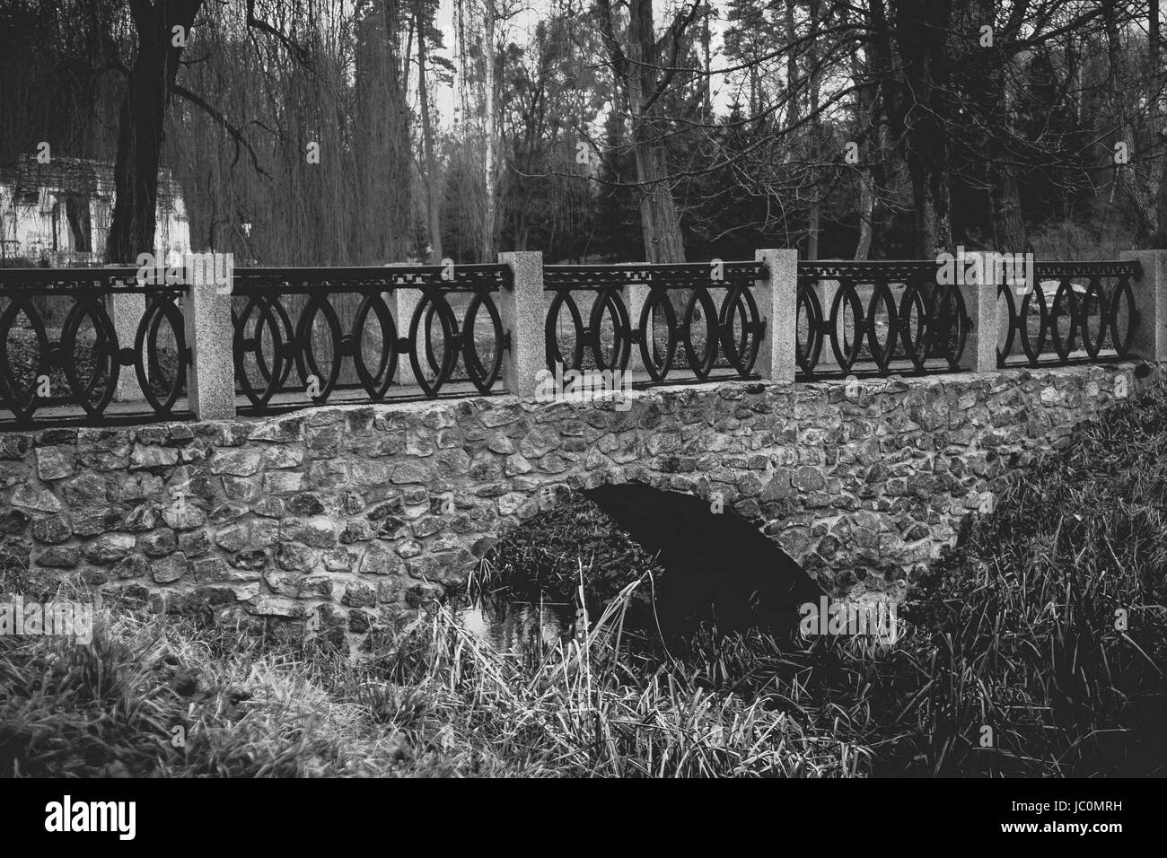 Black and white view of old stone bridge over river at park Stock Photo ...