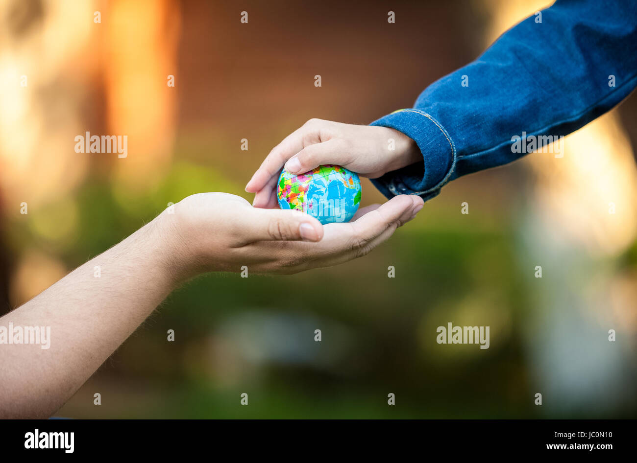 Adult men hand and little girl hands holding planet Earth Stock Photo ...