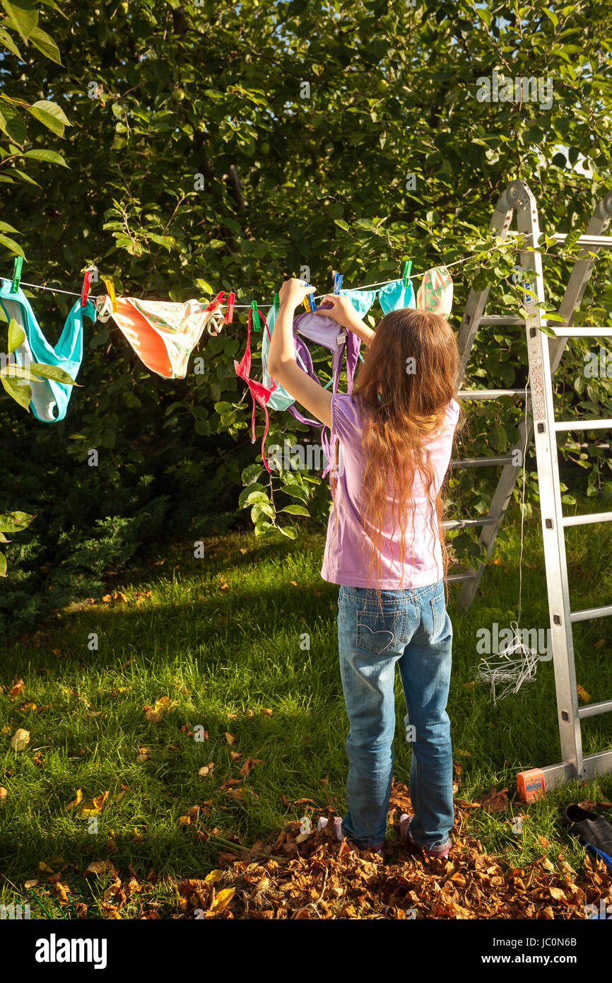 Young girl hanging clothes on clothesline at garden Stock Photo - Alamy