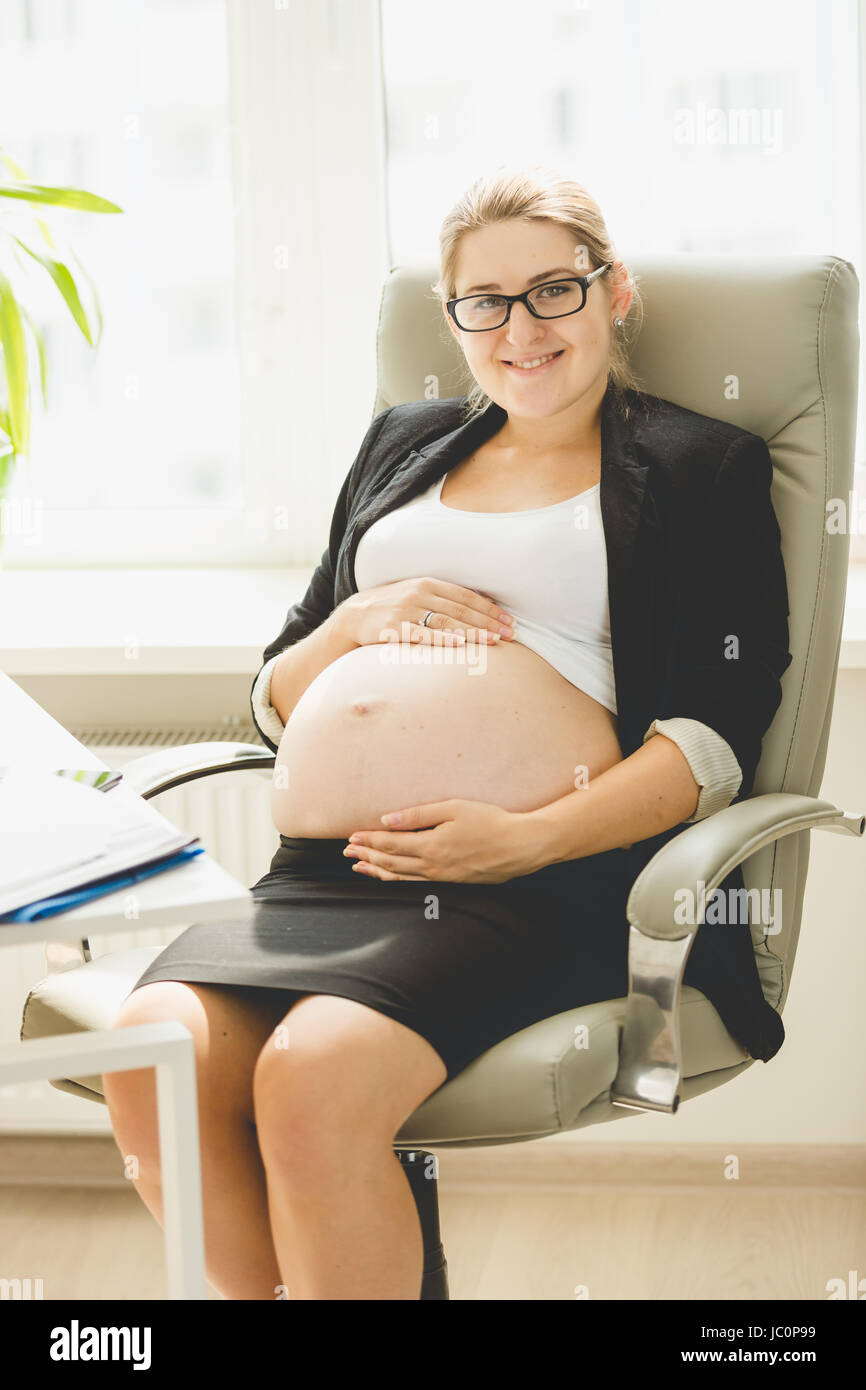 https://c8.alamy.com/comp/JC0P99/happy-pregnant-woman-posing-on-chair-at-office-JC0P99.jpg