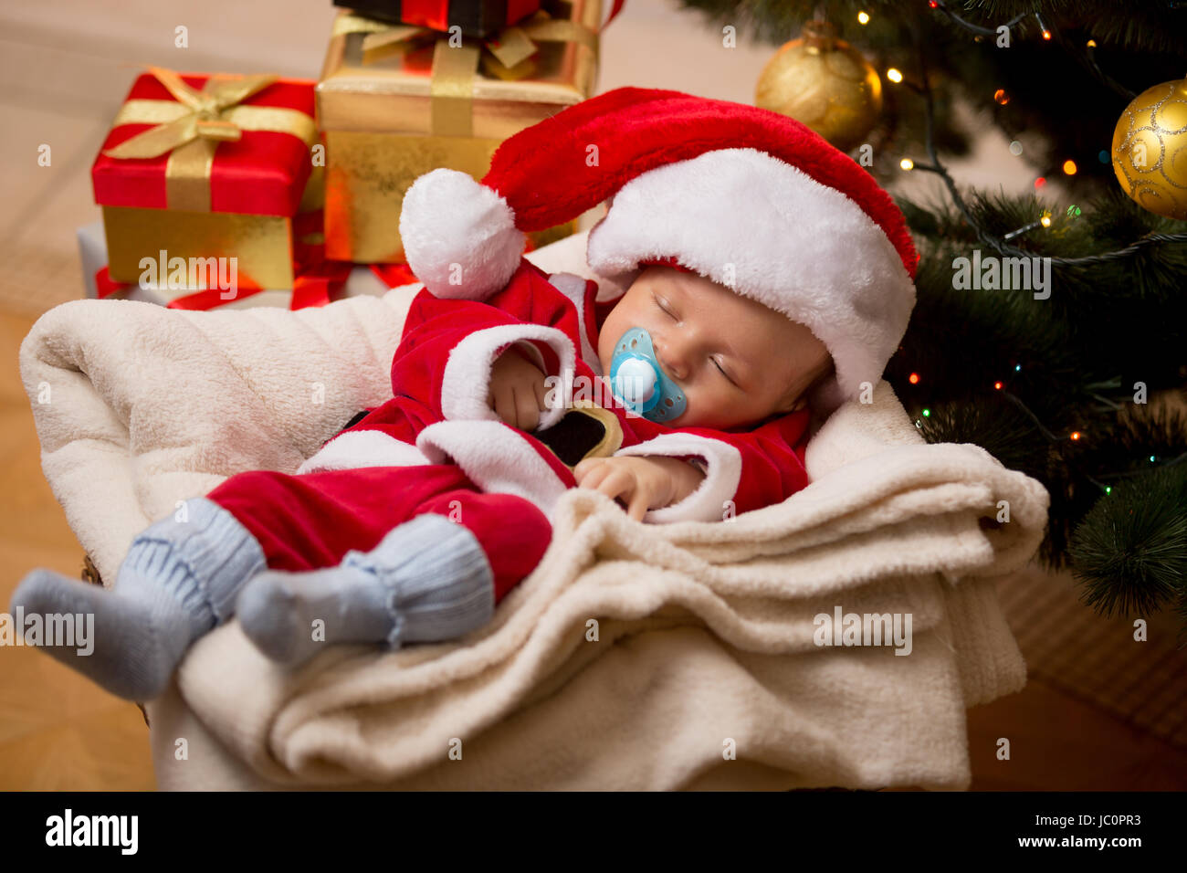 Newborn baby boy sleeping in living room at Christmas tree and boxes