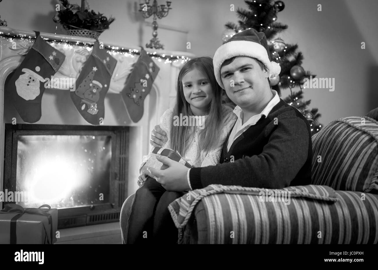 Black and white portrait of happy man and girl sitting at fireplace at Christmas Stock Photo
