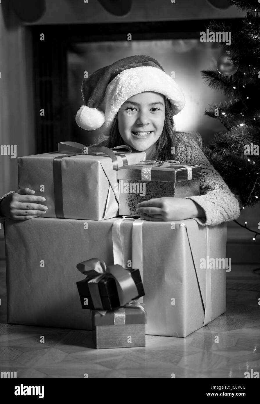Black and white portrait of cute smiling girl posing with Christmas gift boxes Stock Photo