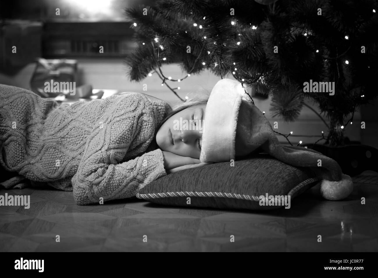 Black and white portrait of cute girl sleeping under Christmas tree Stock Photo