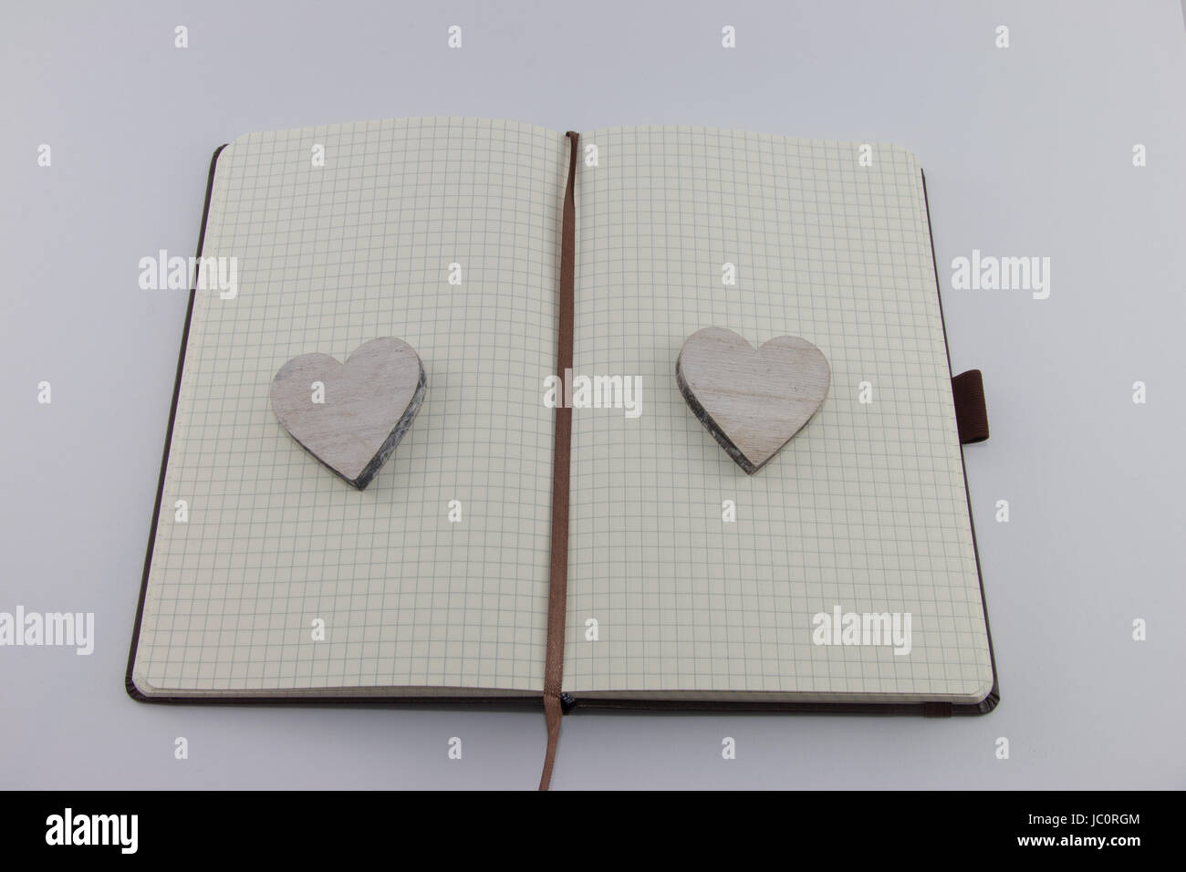 Aufgeschlagenes Notizbuch mit Herzen aus Holz auf jeder Seite liegend Stock Photo