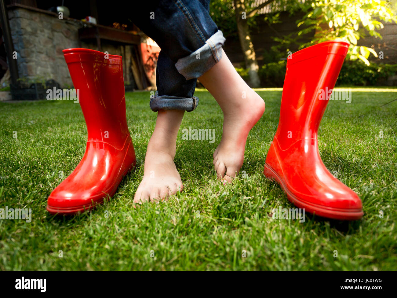 Closeup photo of barefoot girl standing on grass with red rubber boots Stock Photo Alamy