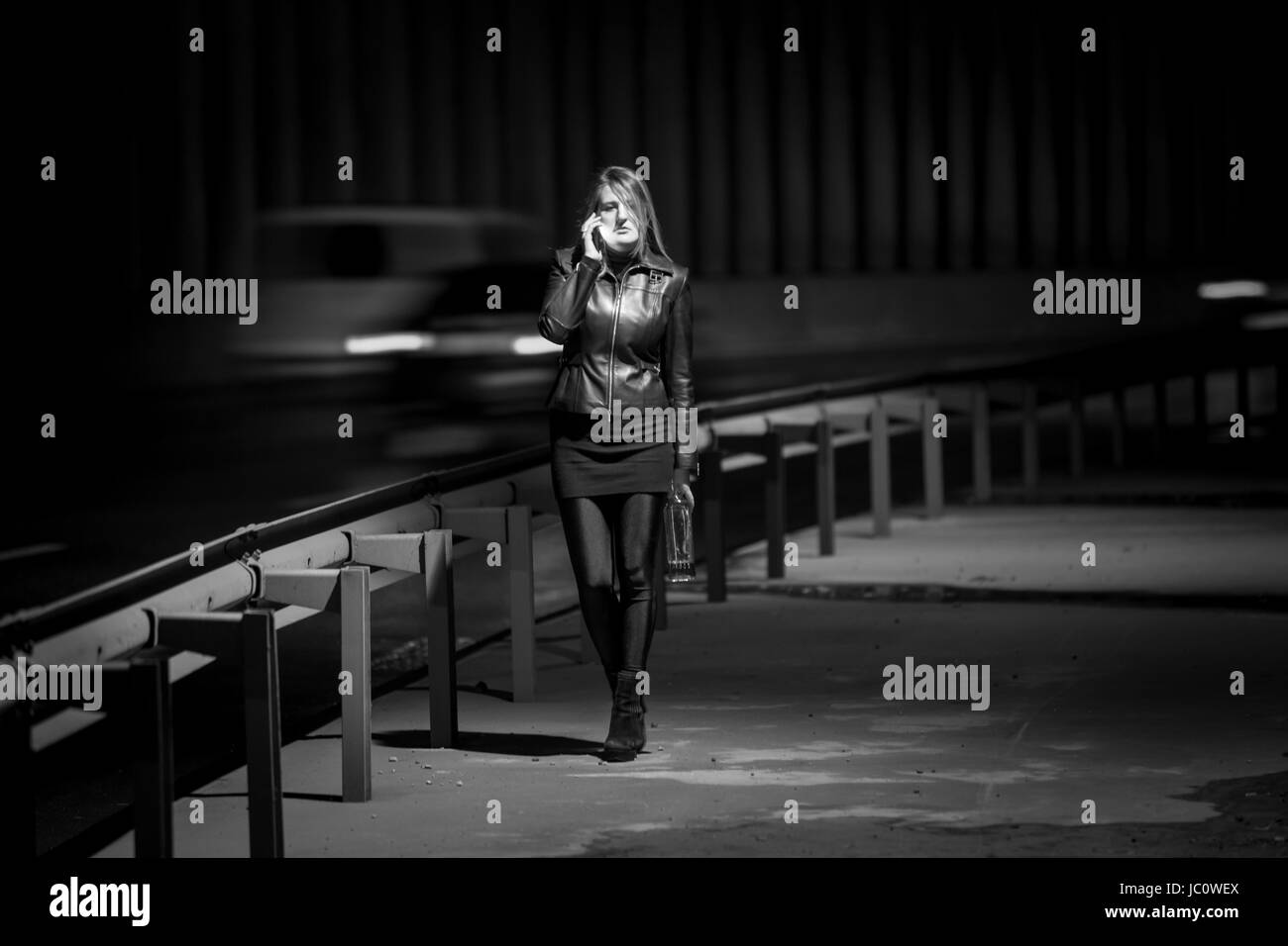 Black and white photo of lonely woman walking at highway at night Stock Photo