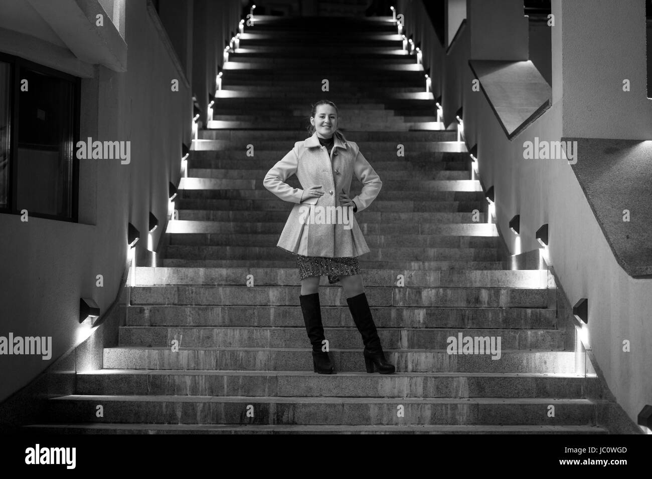 Black and white photo of elegant woman posing on stairs at night Stock Photo