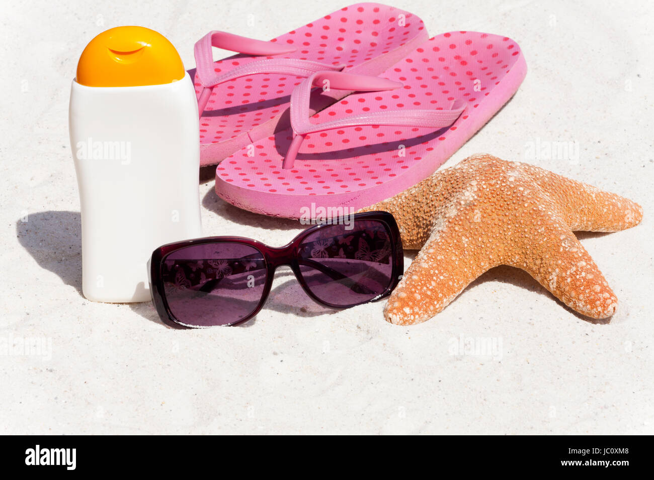 Sonnenmilch, Sonnenbrille, Flip-Flops und ein Seestern am Strand Stock Photo