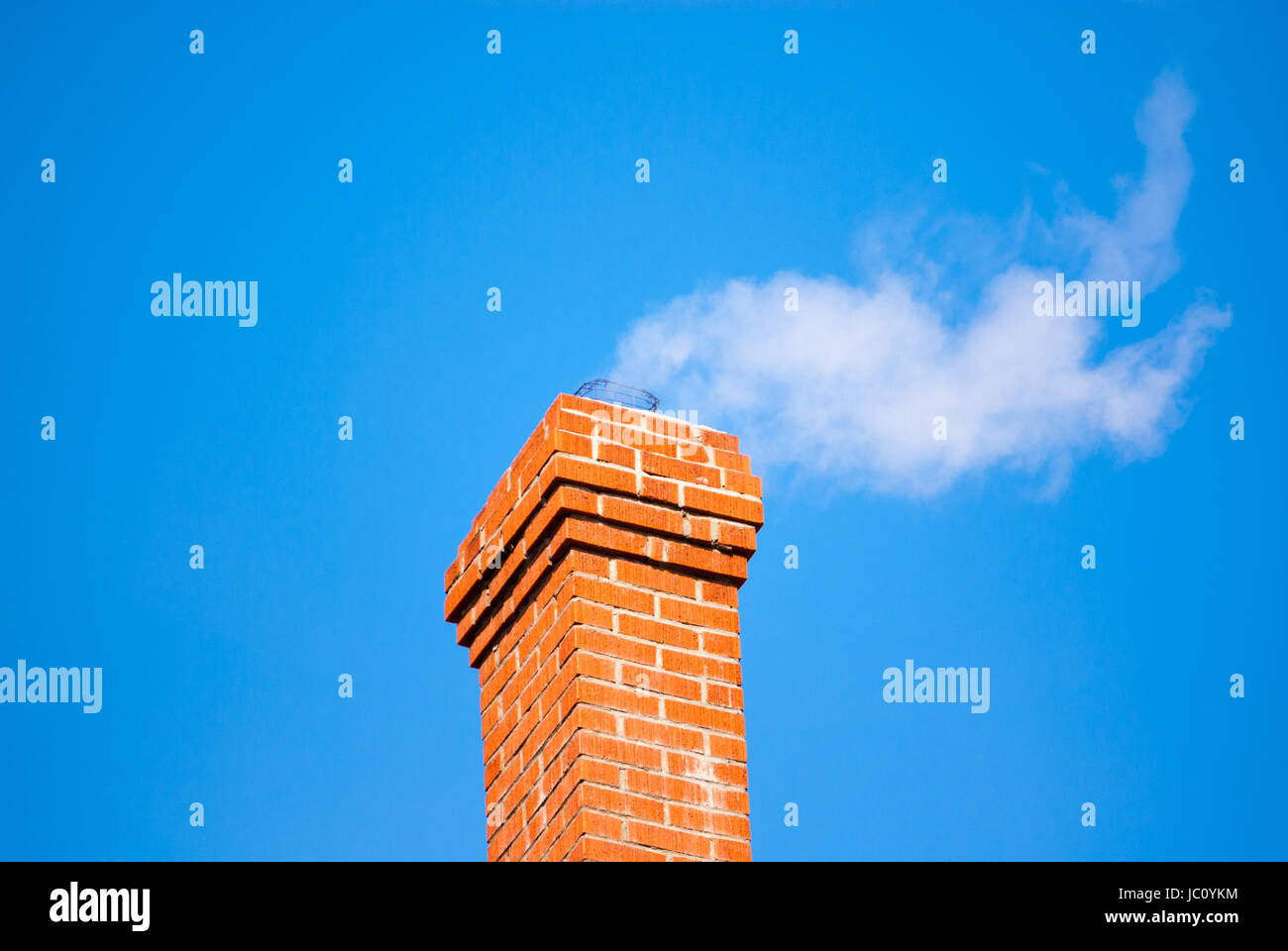 Red brick chimney releasing white smoke on clear blue sky Stock Photo ...