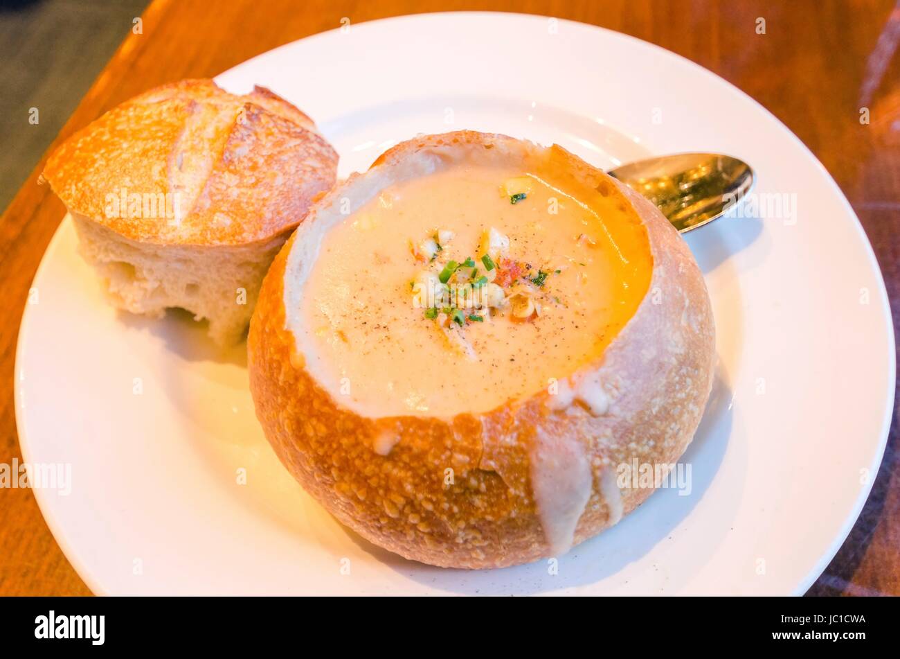 Close up of a Sourdough Clam Chowder gourmet dish. A creamy soup made of clams and vegetables served in a loaf of bread by removing the top, a delicious meal in the Fisherman's wharf in San Francisco. Stock Photo