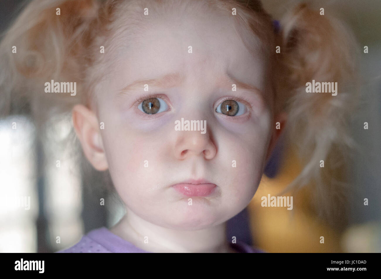 Close up portrait of a cute little redhead girl with a sad pouting ...