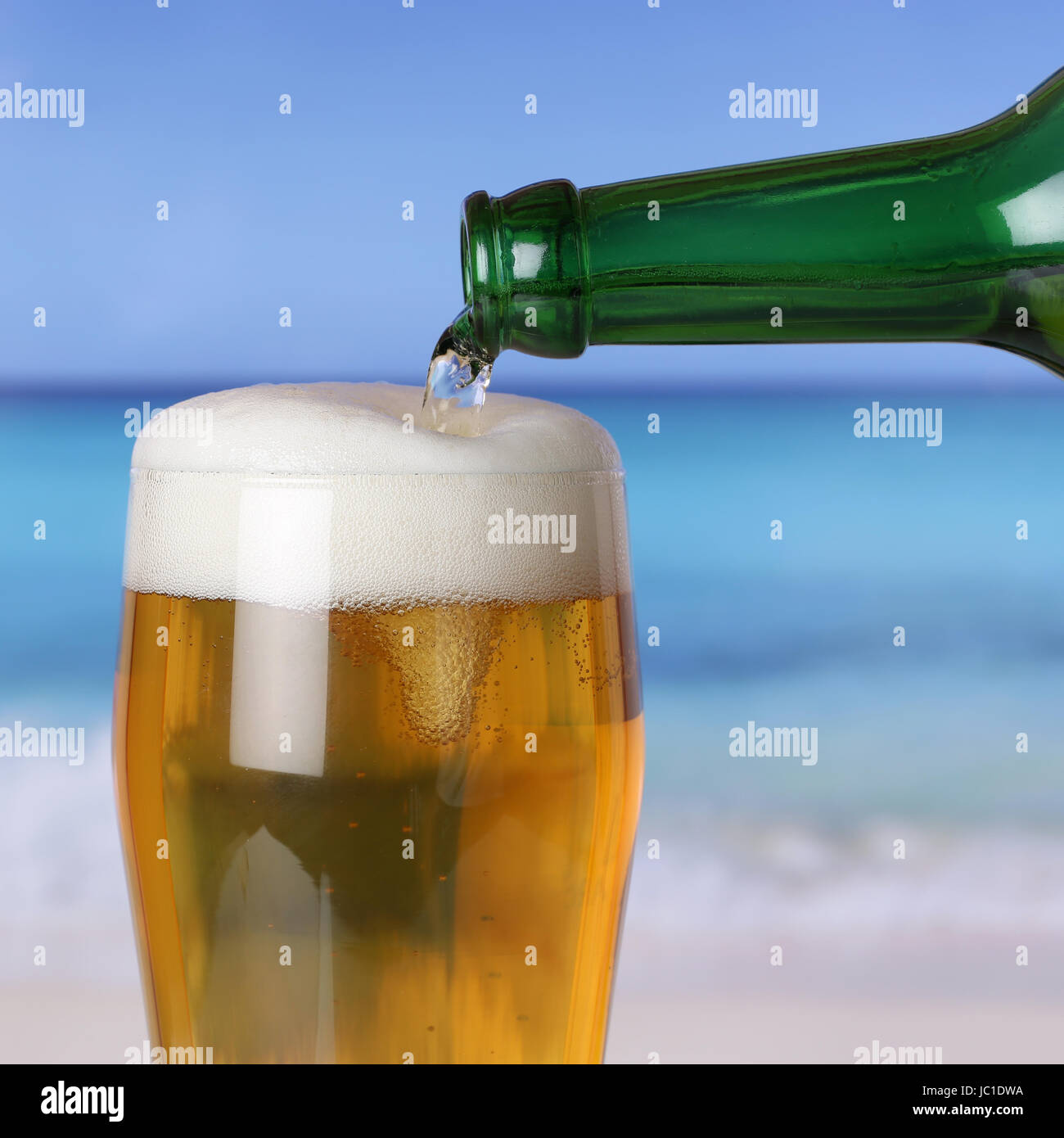 Bier eingießen aus einer Flasche ins Glas am Strand und Meer Stock Photo