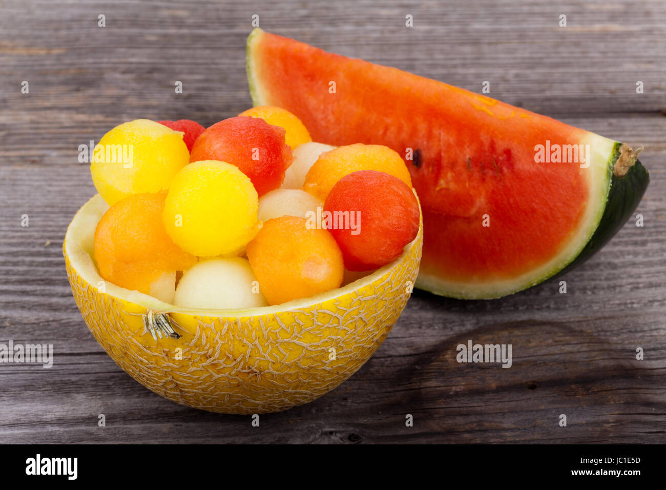 Bunte Melonenbällchen in Schalen aus Melonen auf Holzuntergrund Stock Photo