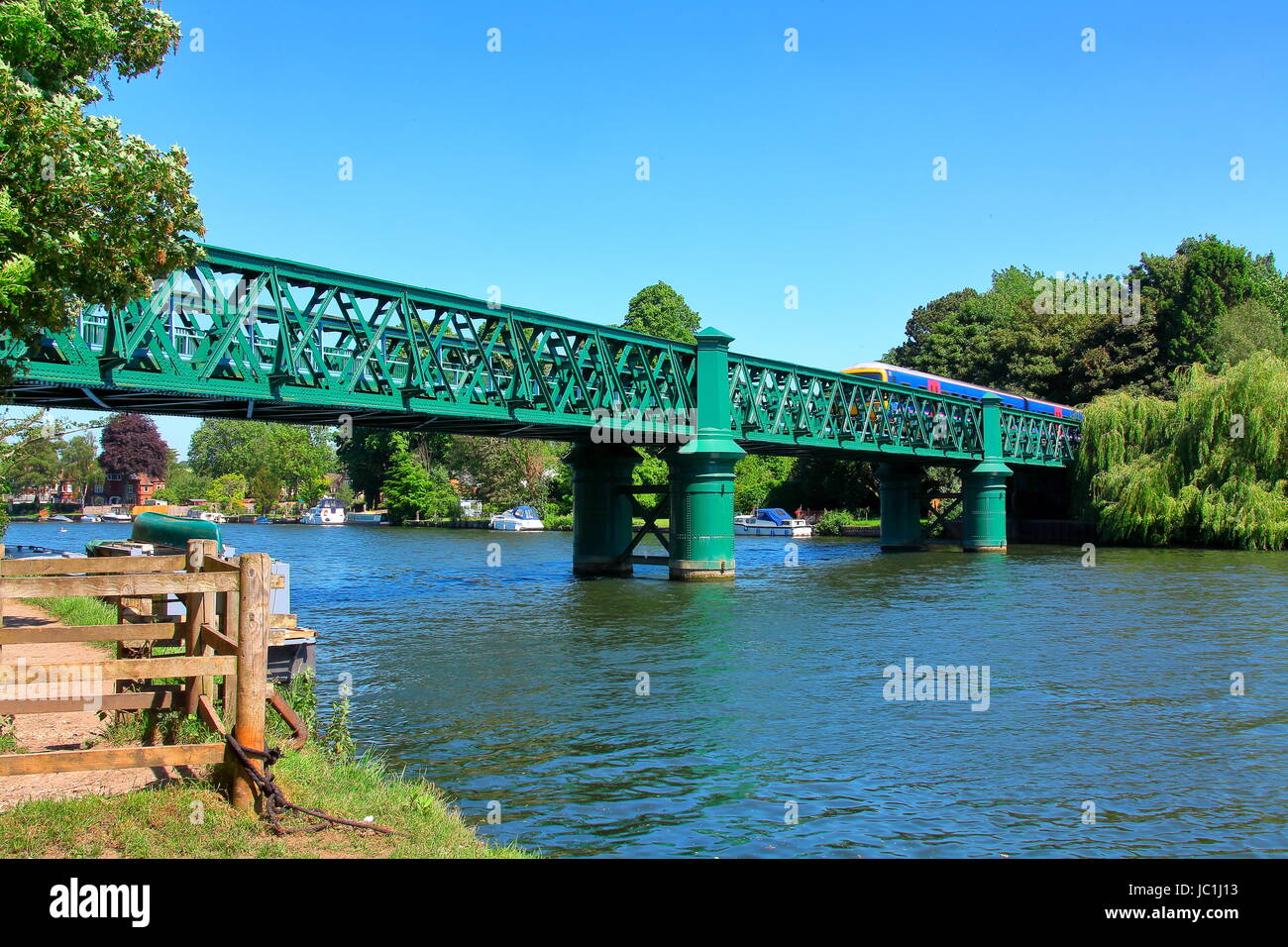 Green painted steel bridge over the Thames at Bourne end with a train