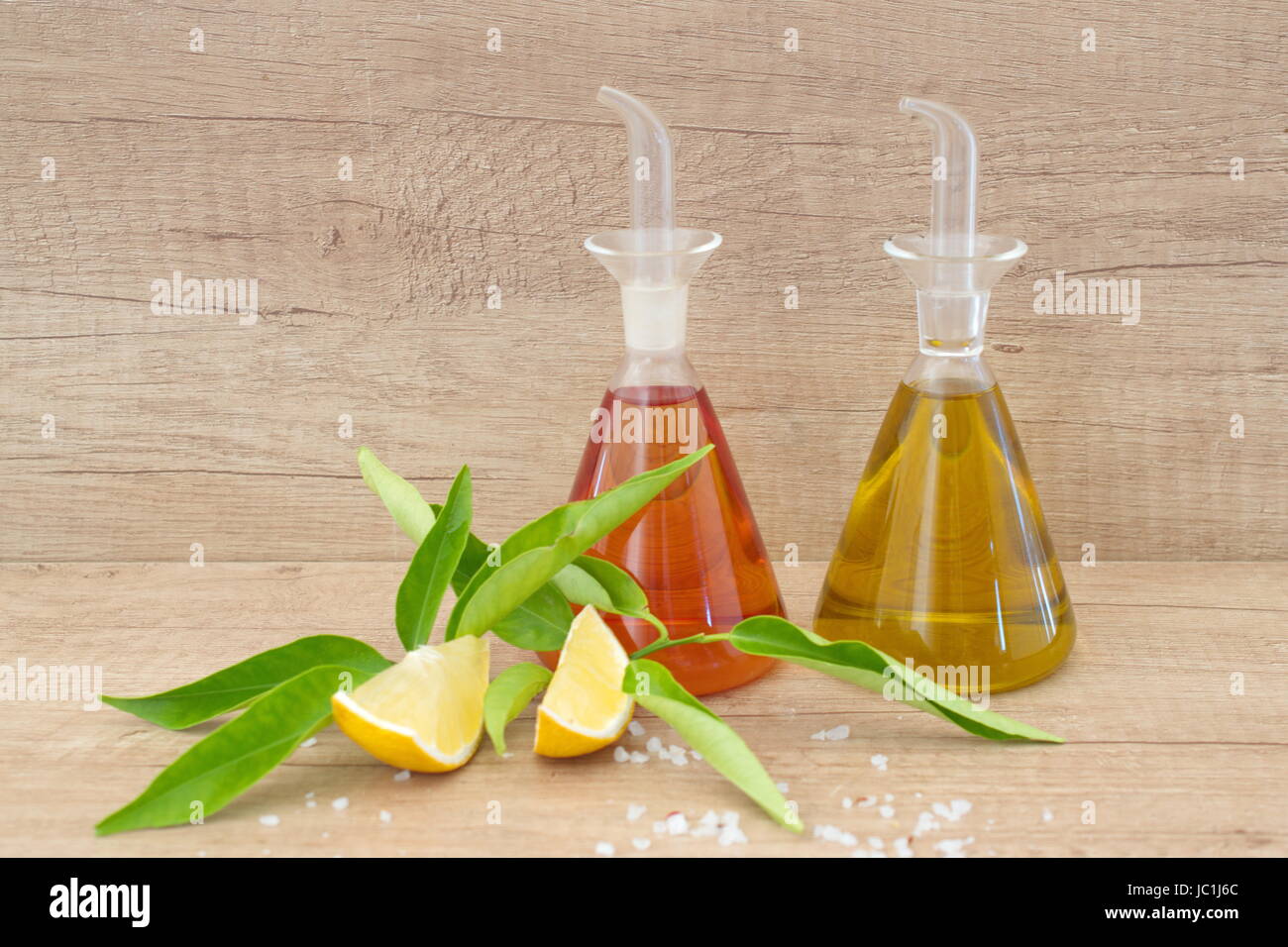 Glass containers with olive oil and vinegar , sea salt, lemon on a wooden background. Traditional greek food. Stock Photo