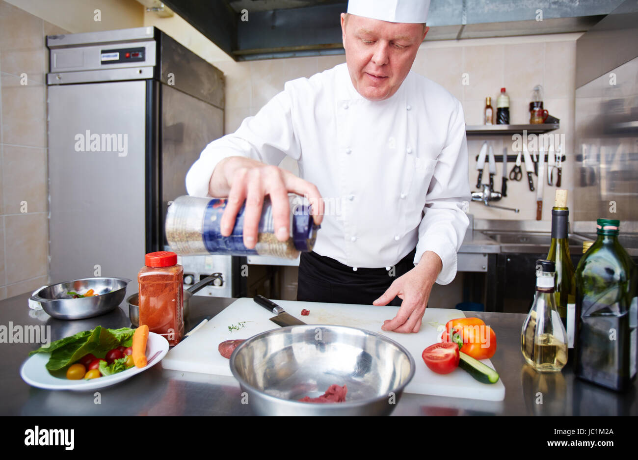 Image of male chef adding spices to meat in bowl Stock Photo - Alamy