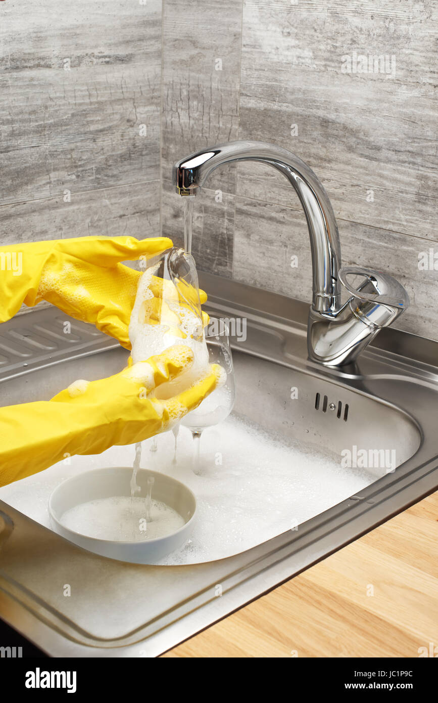 Close up of female hands in yellow protective rubber gloves washing ...