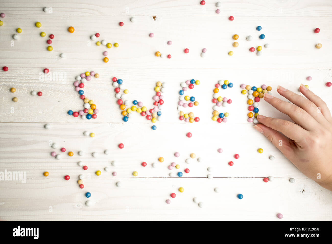 Closeup photo of woman making word Sweet from colorful candies Stock ...