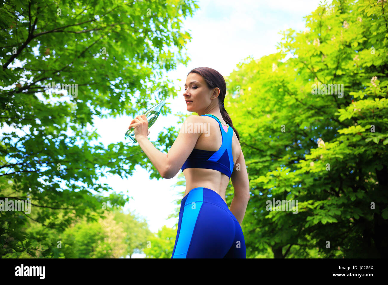 Working out scene. Girl with water bottle on green nature background. Summer healthy lifestyle background. Stock Photo