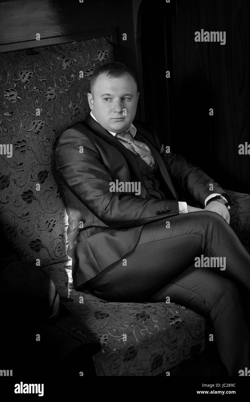 Black and white portrait of man in retro suit sitting in train coupe Stock Photo