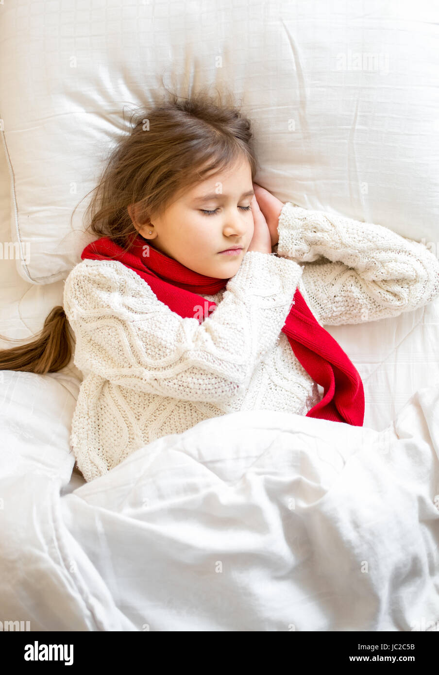 Closeup portrait of little girl in sweater sleeping at bed Stock Photo