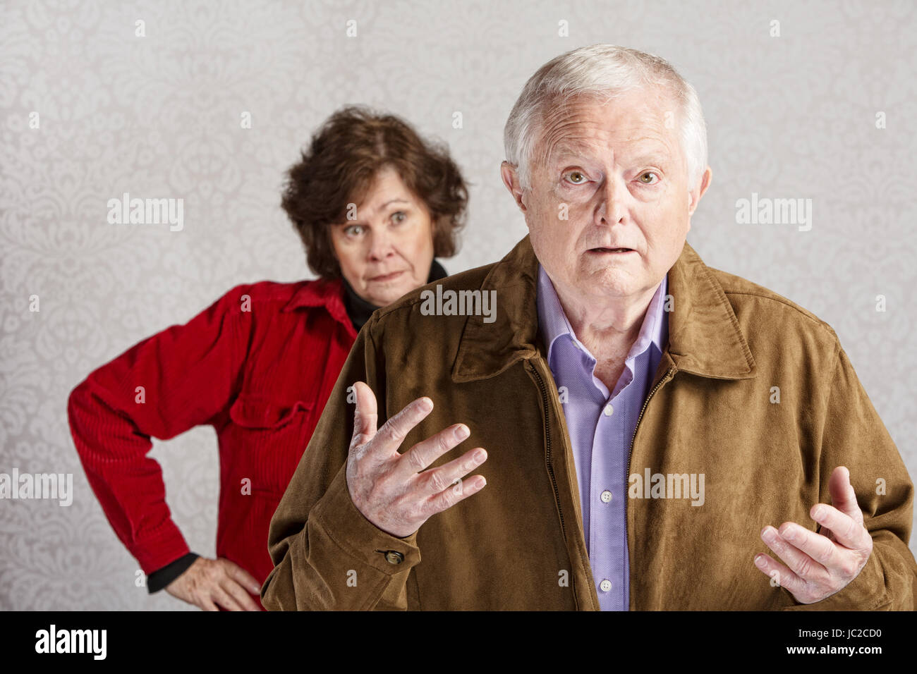 Frustrated older man with hands up and annoyed woman Stock Photo