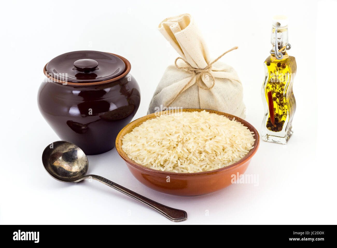 Still life of Steamed rice cereal in ceramic pial, ceramic pot, old spoon and canvas bag for cereals, oil with spices and seasonings, isolated on whit Stock Photo