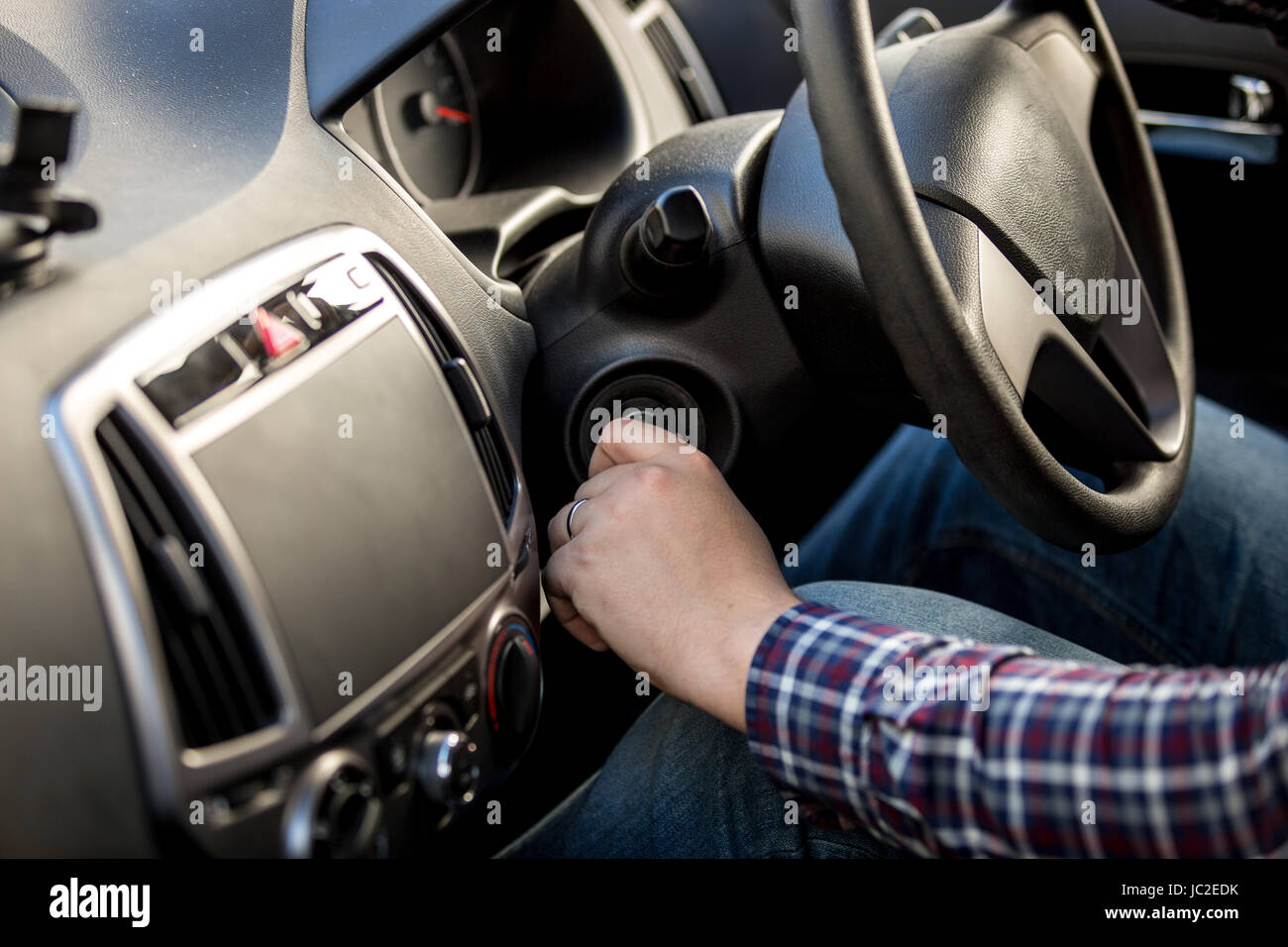 Male driver turning ignition key in righthand drive car Stock Photo