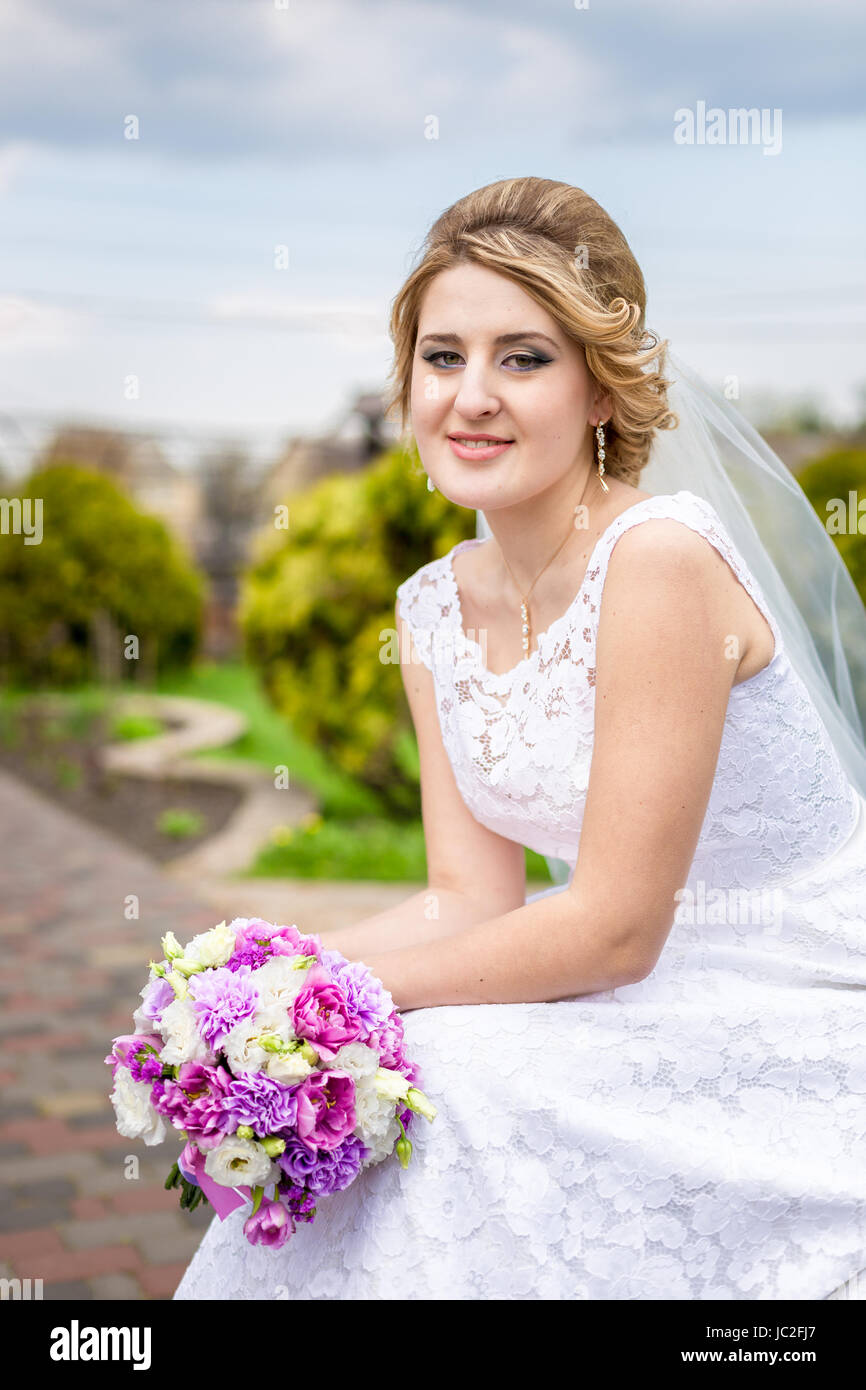 Closeup portrait of happy bride posing at park with bouquet Stock Photo ...